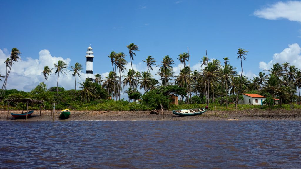 Imagem do Farol Preguiças, barcos e palmeiras