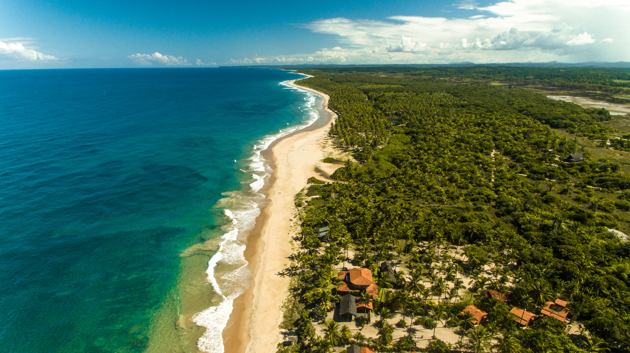 Praia de Algodoes na Peninsula de Marau - BA, com uma extensa faixa de areia branca, vegetação nativa e mar cristalino.